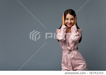 Photo Portrait of a cute woman girl with dark hair in pink clothes on a gray background in the Photo Portrait of a cute woman girl with dark hair in pink clothes on a gray background in the 56742333