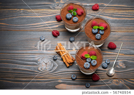 Classic tiramisu dessert with blueberries and strawberries in a glass cup on wooden background 56748934