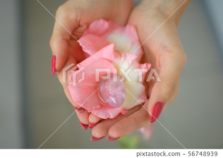 Close up photo of female hand with transparent amethyst yoni egg for vumbuilding inside pink 56748939