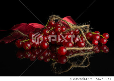 Fresh red currant isolated on black glass Fresh red currant isolated on black glass 56750235