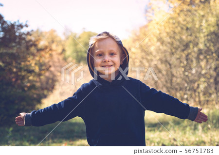 Smiling blond boy with open arms in the hood. 56751783