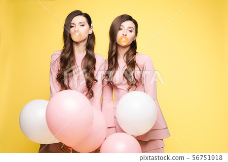 Young twins holding pink and white balloons in Young twins holding pink and white balloons in 56751918