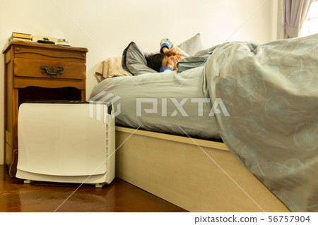 Air purifier in the bed room with young boy stretching on the bed. 56757904