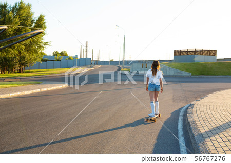 stylish girl in white stockings ride on longboard 56767276