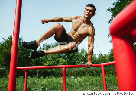 Young muscular man while doing his workout outside at playground 56769710