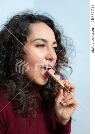 Girl eats a chocolate and shows emotions Girl eats a chocolate and shows emotions 56775752