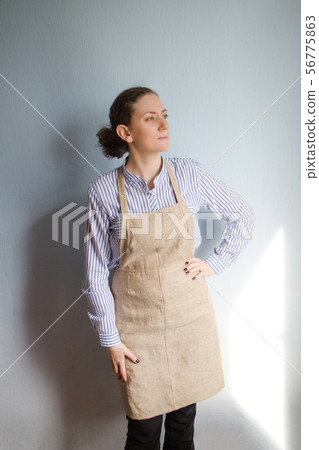 Young woman in a cotton apron near blue wall 56775863