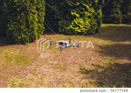 man and his drone, quadrocopter in a forest on a green background. 56777549