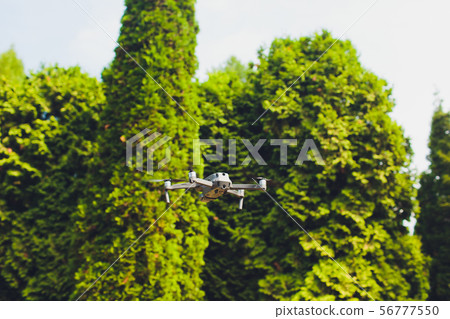 man and his drone, quadrocopter in a forest on a green background. 56777550