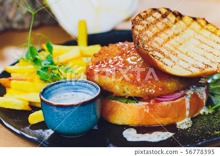 Vegetarian lentil burger in wholewheat bun with lettuce, tomato and cucumber accompanied by French Vegetarian lentil burger in wholewheat bun with lettuce, tomato and cucumber accompanied by French 56778395