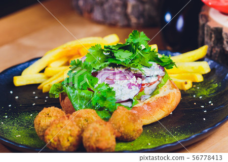 Vegetarian lentil burger in wholewheat bun with lettuce, tomato and cucumber accompanied by French Vegetarian lentil burger in wholewheat bun with lettuce, tomato and cucumber accompanied by French 56778413