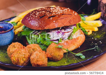 Vegetarian lentil burger in wholewheat bun with lettuce, tomato and cucumber accompanied by French Vegetarian lentil burger in wholewheat bun with lettuce, tomato and cucumber accompanied by French 56778414