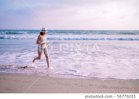 young woman on sunset beach and joyful running . young woman on sunset beach and joyful running . 56779283