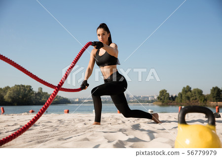 Young healthy female athlete doing workout at the beach 56779979