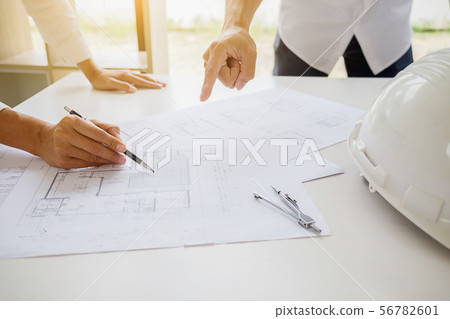 Engineers discuss a blueprint while checking 56782601