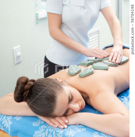 Pretty girl getting hot stone massage in spa salon 56784198