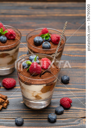 Classic tiramisu dessert with blueberries and strawberries in a glass cup on wooden background 56790000
