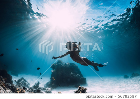 Woman freediver with fins swim over sandy sea 56792587