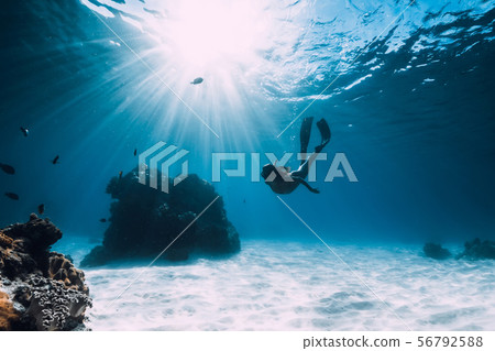 Woman free diver with fins glides over sandy 56792588