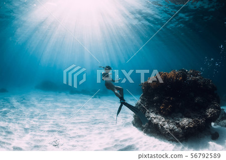 Freediver young woman with fins glides over sand 56792589