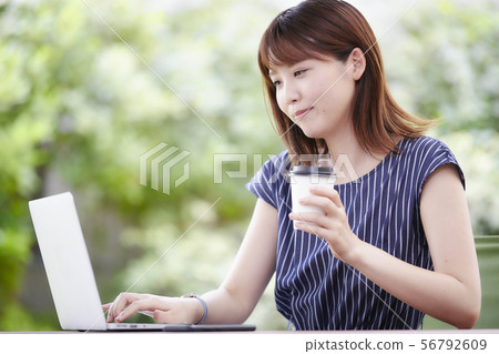 A business woman who operates a personal computer at an open cafe 56792609