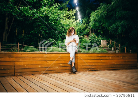 Smiling young woman sitting relaxed on bench Smiling young woman sitting relaxed on bench 56796611