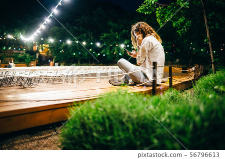 Rear view young woman sitting on bench using smart Rear view young woman sitting on bench using smart 56796613