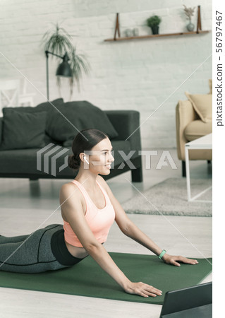 Happy woman exercising at home near tablet stock photo Happy woman exercising at home near tablet stock photo 56797467