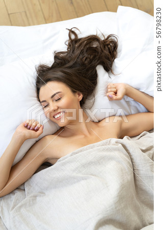 Joyful young woman waking up in her bedroom Joyful young woman waking up in her bedroom 56798230