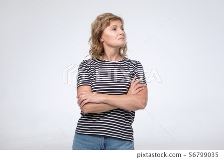 Caucasian arrogant mature woman wth folded hands looking aside. 56799035