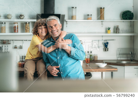 Little kid hugging father on kitchen at home 56799240