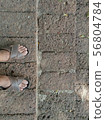 The feet of people standing on the stairs made of 56804784