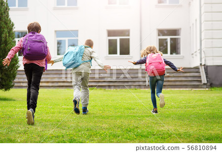 Children with rucksacks standing in the park near school Children with rucksacks standing in the park near school 56810894