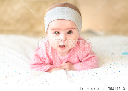 Adorable baby girl with grey headband looking towards camera and smiling. Health concept Adorable baby girl with grey headband looking towards camera and smiling. Health concept 56814540
