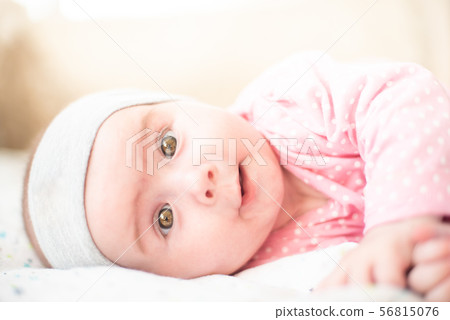 Adorable baby girl in pink lie on side and looking towards camera and smiling. Health concept 56815076