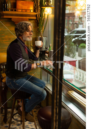 Thoughtful man drinking coffee looking at people passing by. 56817762