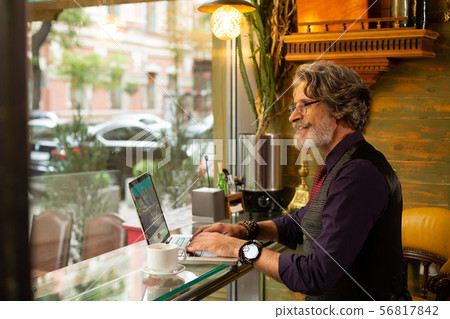 Smiling man working sitting in a coffee shop. 56817842