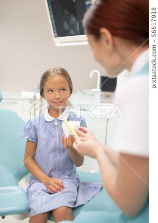 Girl sitting on dental chair and listening to doctor attentively Girl sitting on dental chair and listening to doctor attentively 56817918