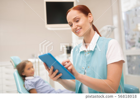 Child dentist smiling while studying clinical record Child dentist smiling while studying clinical record 56818018