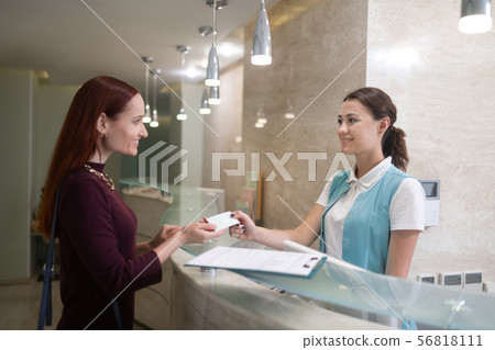 Smiling receptionist of dentistry giving contact details for client 56818111