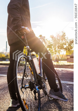The cyclist is standing near road bike The cyclist is standing near road bike 56818647