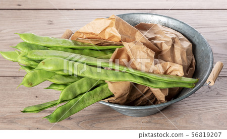 bunch of flat beans on a wooden board. bunch of flat beans on a wooden board. 56819207