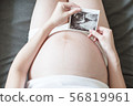 Pregnant women holding a sonogram 56819961