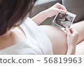 Pregnant women holding a sonogram 56819963