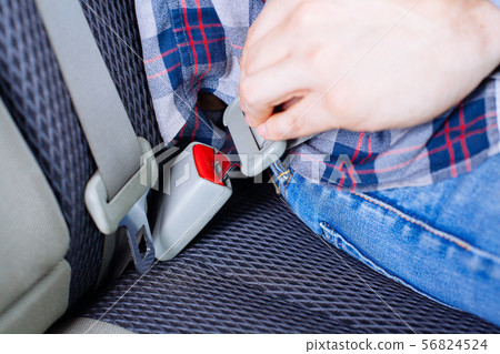 Men's hand fastens the seat belt of the car. 56824524