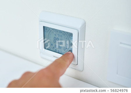 hand setting temperature on control panel 56824976