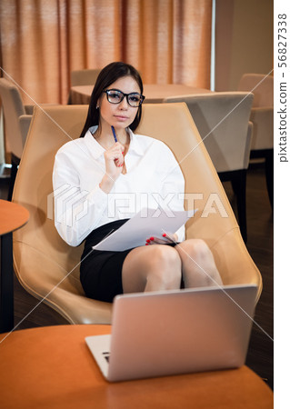 Close-up portrait of casual woman using her laptop while sitting on couch and working. 56827338