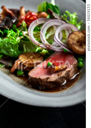 beef tagliata with vegetables. Close-up, low key, gray background. beef tagliata with vegetables. Close-up, low key, gray background. 56829153