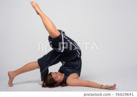 Full body shot of young Asian woman stretching and doing Plow yoga pose 56829641