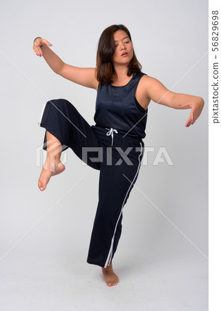 Young beautiful Asian woman dancing and standing on one leg Young beautiful Asian woman dancing and standing on one leg 56829698